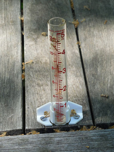 A rain gauge to measure rainfall on a wooden deck
